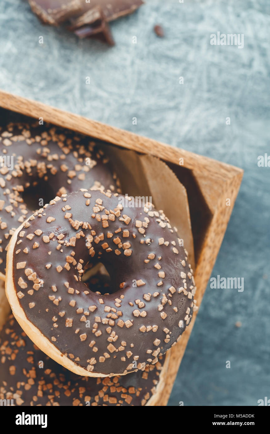 Schokolade Donuts in einem hölzernen Kasten auf einem grauen strukturierten Hintergrund. Flach. Stockfoto