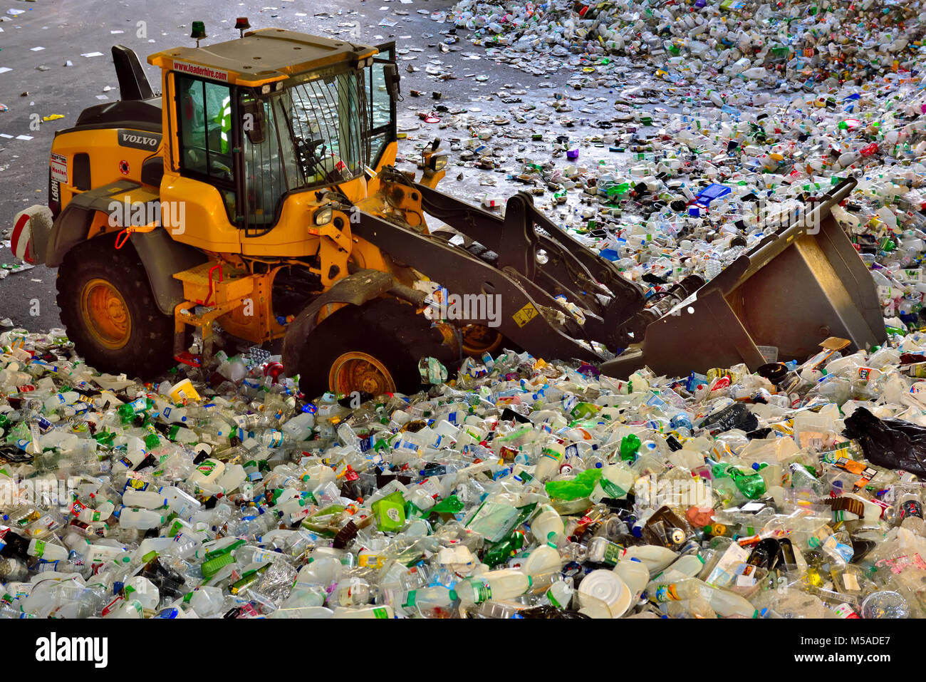 Post consumer Abfälle, Plastikflaschen und Dosen, in Recyclinganlage durch Sammlung Lkw vom Traktor zum Sortieren bewegt wird, Großbritannien Stockfoto