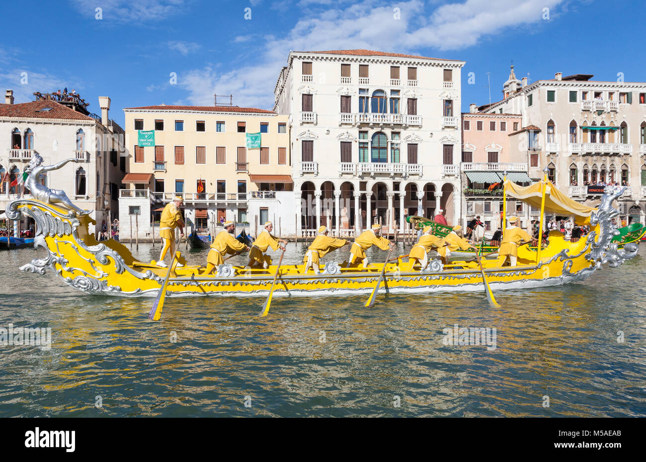 Historische Boote in der Regata Storica, Grand Canal, Venice, Italien mit Ruderer in einem hellen Gelb Boot mit passenden Kostüme tragen einer dignatory Stockfoto