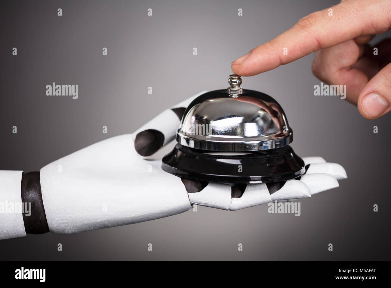 Die Person Ringing Service Bell halten durch Roboter auf grauem Hintergrund Stockfoto