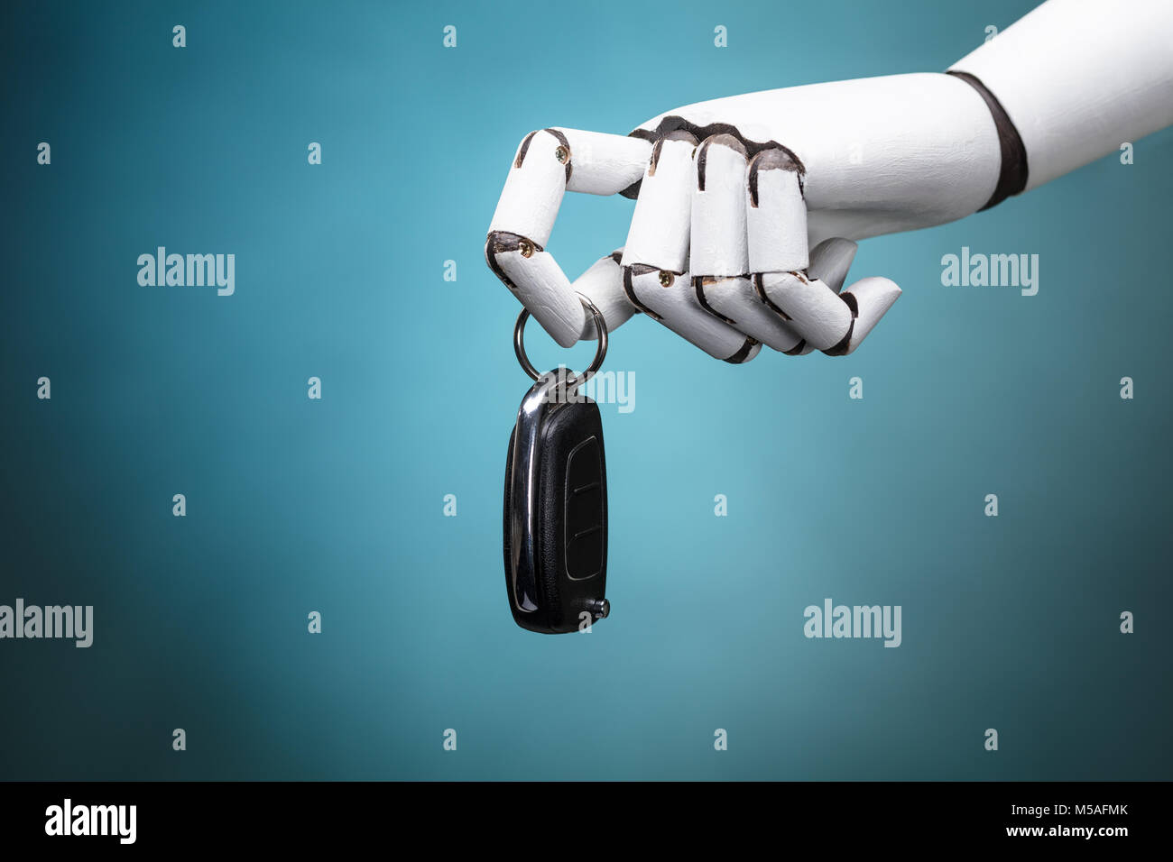 Nahaufnahme eines Roboters Holding Autoschlüssel auf Türkisfarbenem Hintergrund Stockfoto