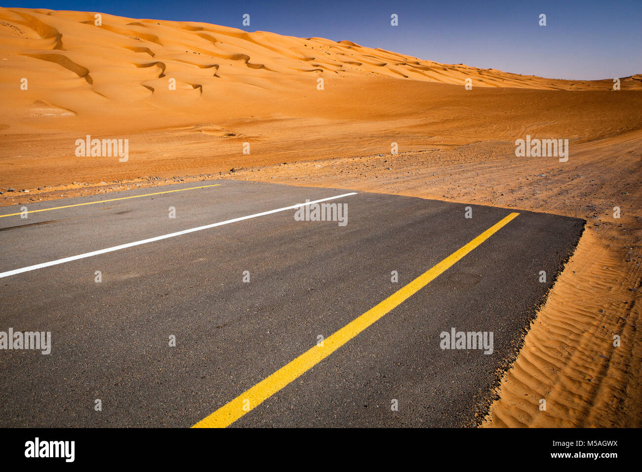 Moderne versus Natur Konzept - Ende der Zivilisation, Beginn der Wüste. Moderne asphaltierte Straße landet in Sanddünen. Stockfoto