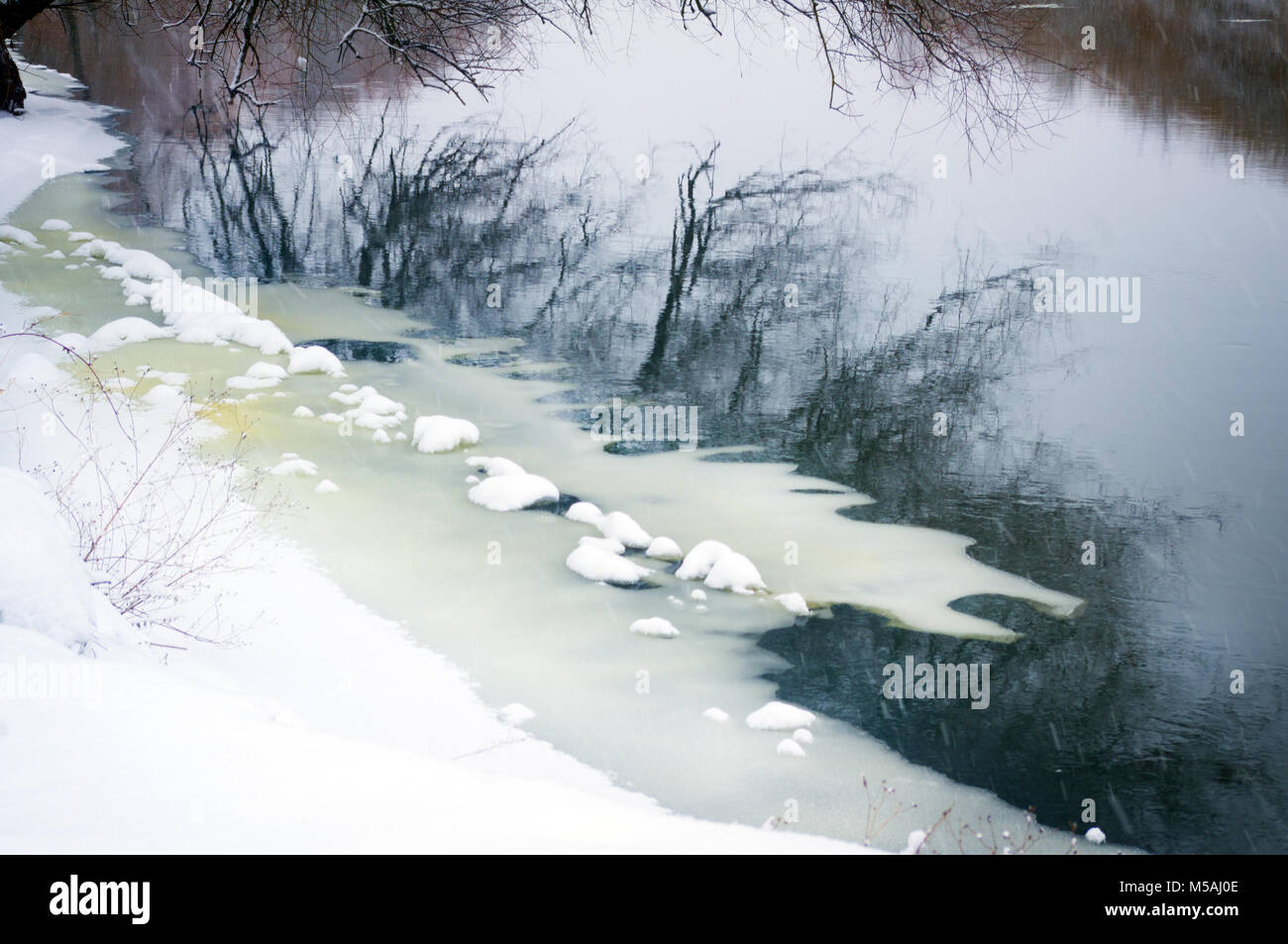 Winter River. Die schneebedeckten Bäumen und der Küste im Wasser spiegelt Stockfoto