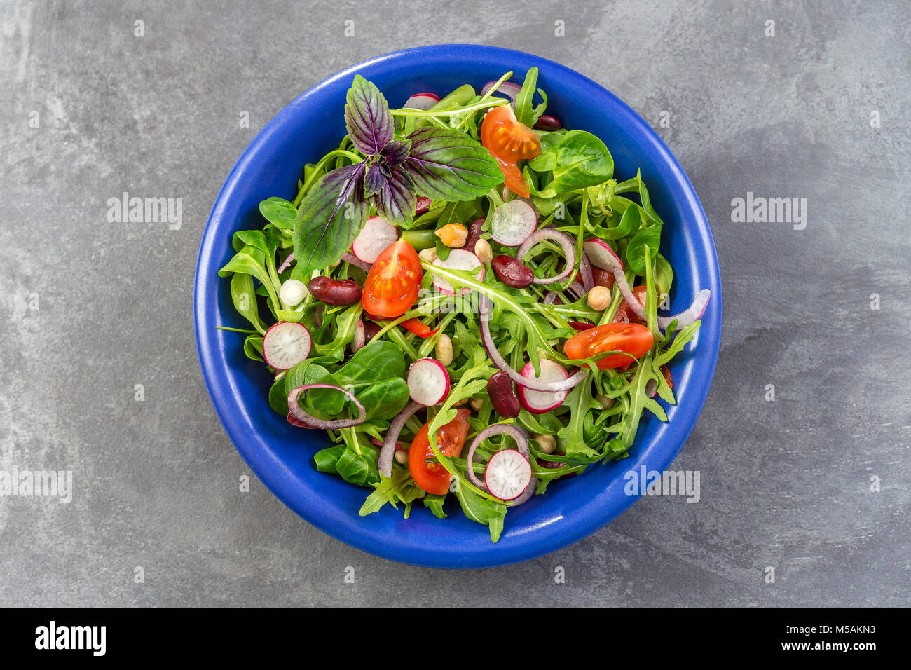 Frische Kraut Salat mit Blattgemüse und kapuzinerkresse Blumen in einem blauen Keramik Schüssel serviert. Stockfoto