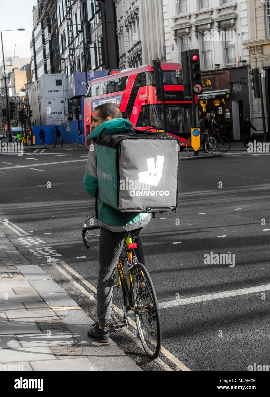 Deliveroo (online Food Delivery Company), Mountainbike/Fahrrad-Fahrer, die mit einem Auftrag in einem Beutel/Container auf dem Rücken, im Zentrum von London, England, UK. Stockfoto