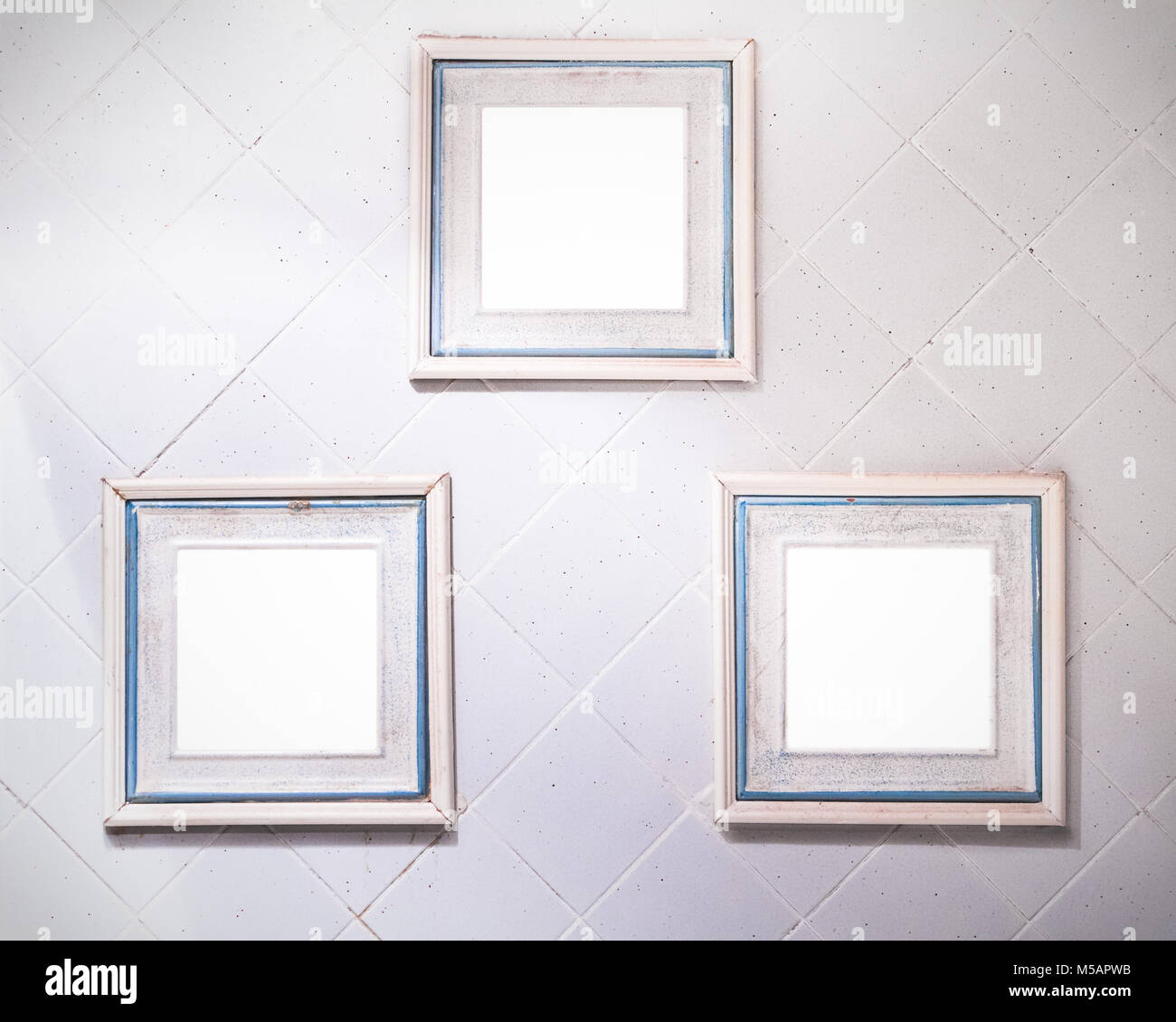 Drei quadratische Rahmen mit Pastellfarben auf einem weiß gefliesten Wand Stockfoto