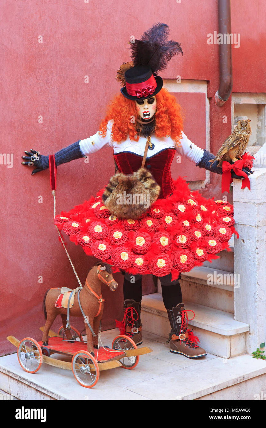 Eine kostümierte Dame mit einem hölzernen Pferd während der Karneval von Venedig (Carnevale di Venezia) in Venedig, Italien Stockfoto