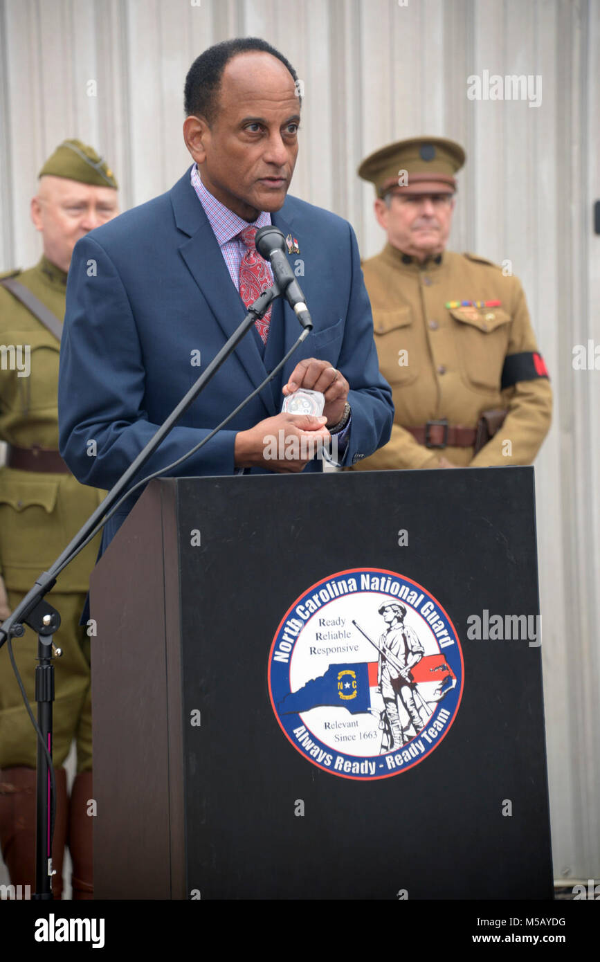 Larry Hall, Sekretär für die North Carolina Abteilung Militär & Veterans Affairs stellen eine staatliche Münze während der Spatenstich für die North Carolina National Guard Museum und das Learning Center of Excellence an der gemeinsamen Kraft Hauptsitz in Raleigh, North Carolina, 13. Februar 2018. Lokalen, staatlichen und North Carolina National Guard Führer sind anwesend für einen spatenstich an der gemeinsamen Kraft von North Carolina National Guard Hauptsitz der Beginn des Baus für die North Carolina National Guard Museum und das Learning Center of Excellence zu feiern. (U.S. Armee Stockfoto