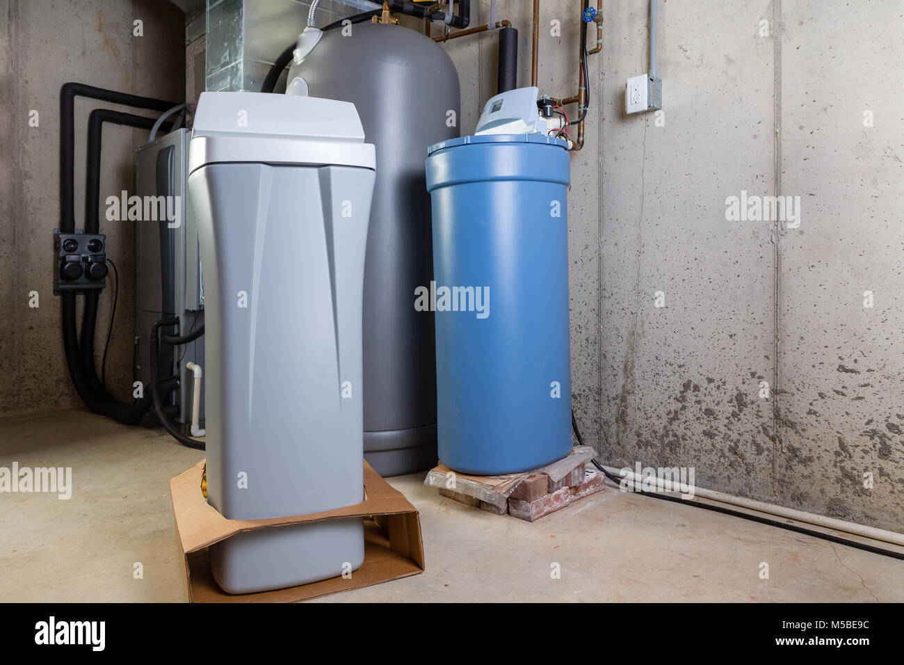 Alte und Neue wasserenthärter Tanks in einem Hauswirtschaftsraum warten auf Ersatz Mineralien aus hartem Wasser zu entfernen. Stockfoto