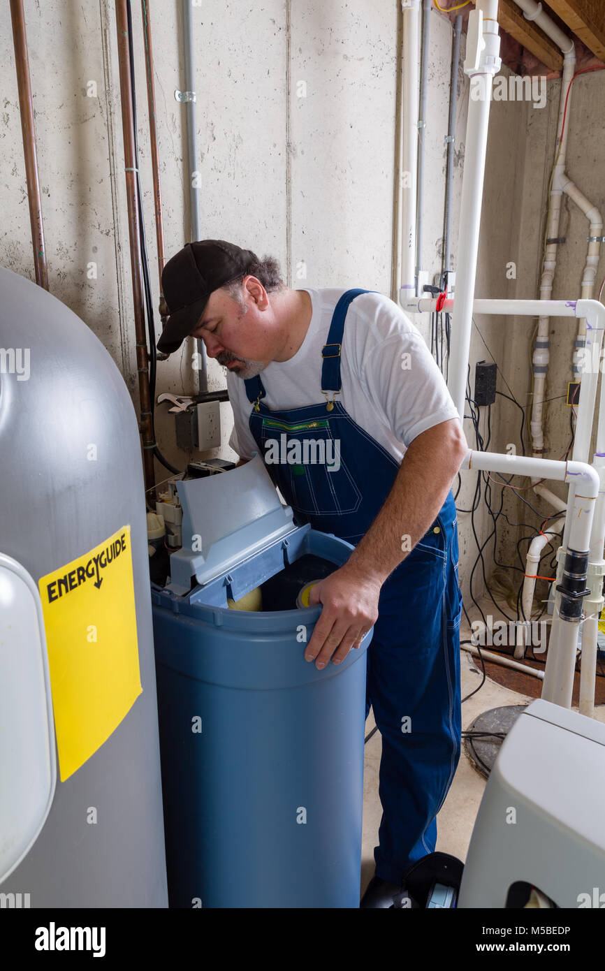 Workman Austausch eines alten heimischen Wasserenthärter in Probleme bei der Installation des neuen Tanks in einem Hauswirtschaftsraum suchen Stockfoto