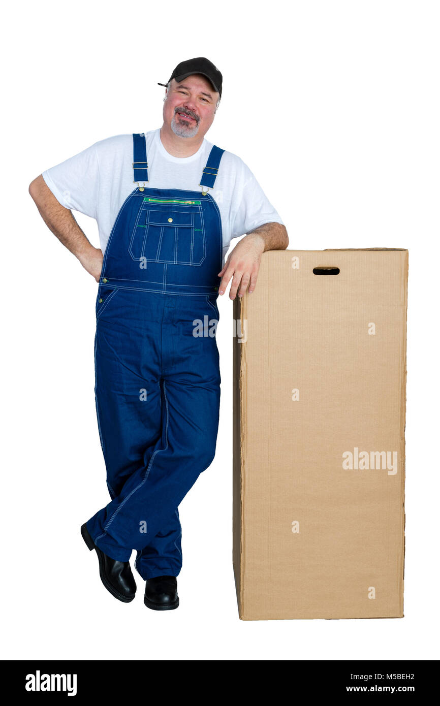 Lächelnder Mann mit Latzhose lehnte sich gegen große Karton auf weißem Hintergrund Stockfoto