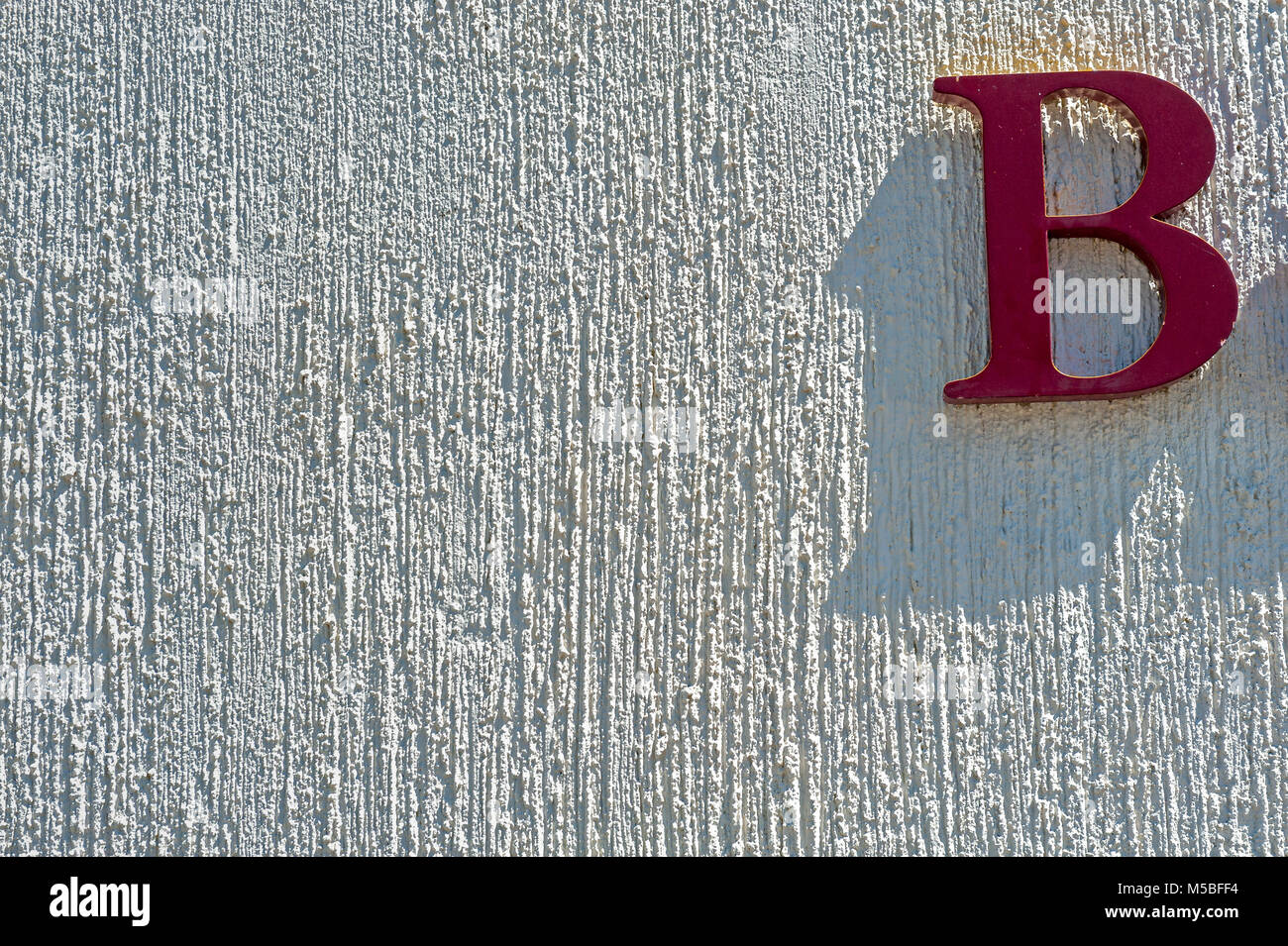 Red Letter B auf weißem Stuck Wand Stockfoto