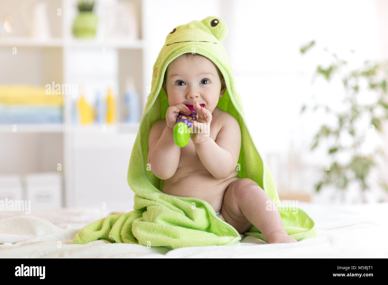Baby mit grünen Handtuch nach dem Bad beißen Spielzeug Stockfoto