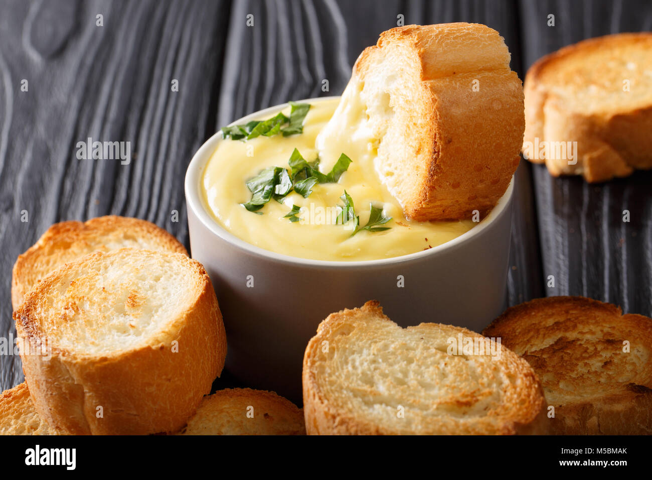 Köstlich getoastetes Brot getaucht in Käsesoße close-up auf dem Tisch. Horizontale Stockfoto