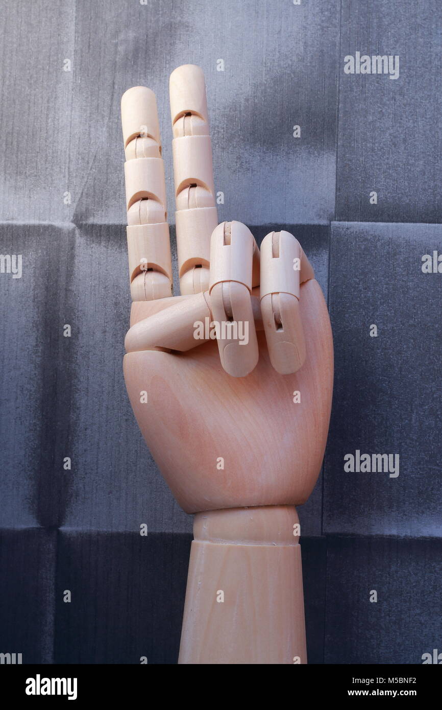 Holz- hand mit zwei Fingern mit einem Vintage lackiert Papier Hintergrund Stockfoto