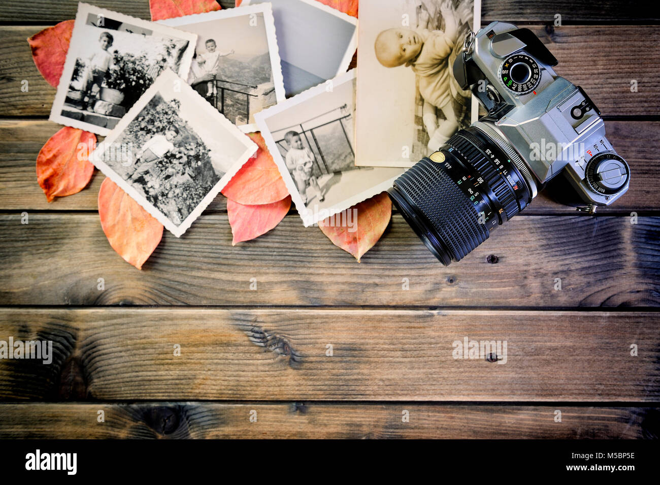 Blick von oben auf eine 35-mm-Kamera, vintage Foto auf dem Hintergrund der Blätter in einem rustikalen Holztisch Stockfoto