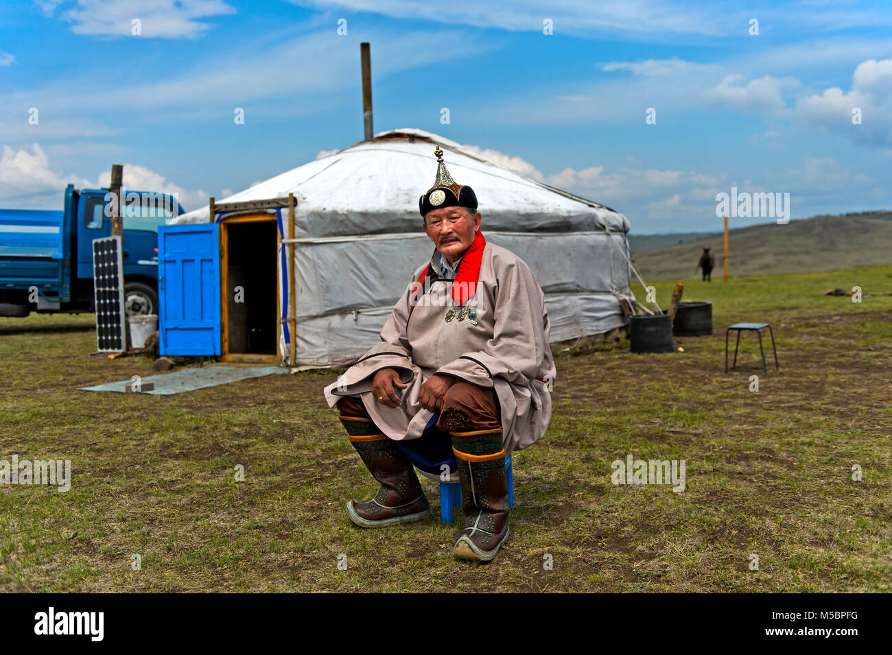 Ältere männliche Nomad in traditioneller Kleidung sitzend vor seinem jurte, Mongolei Stockfoto