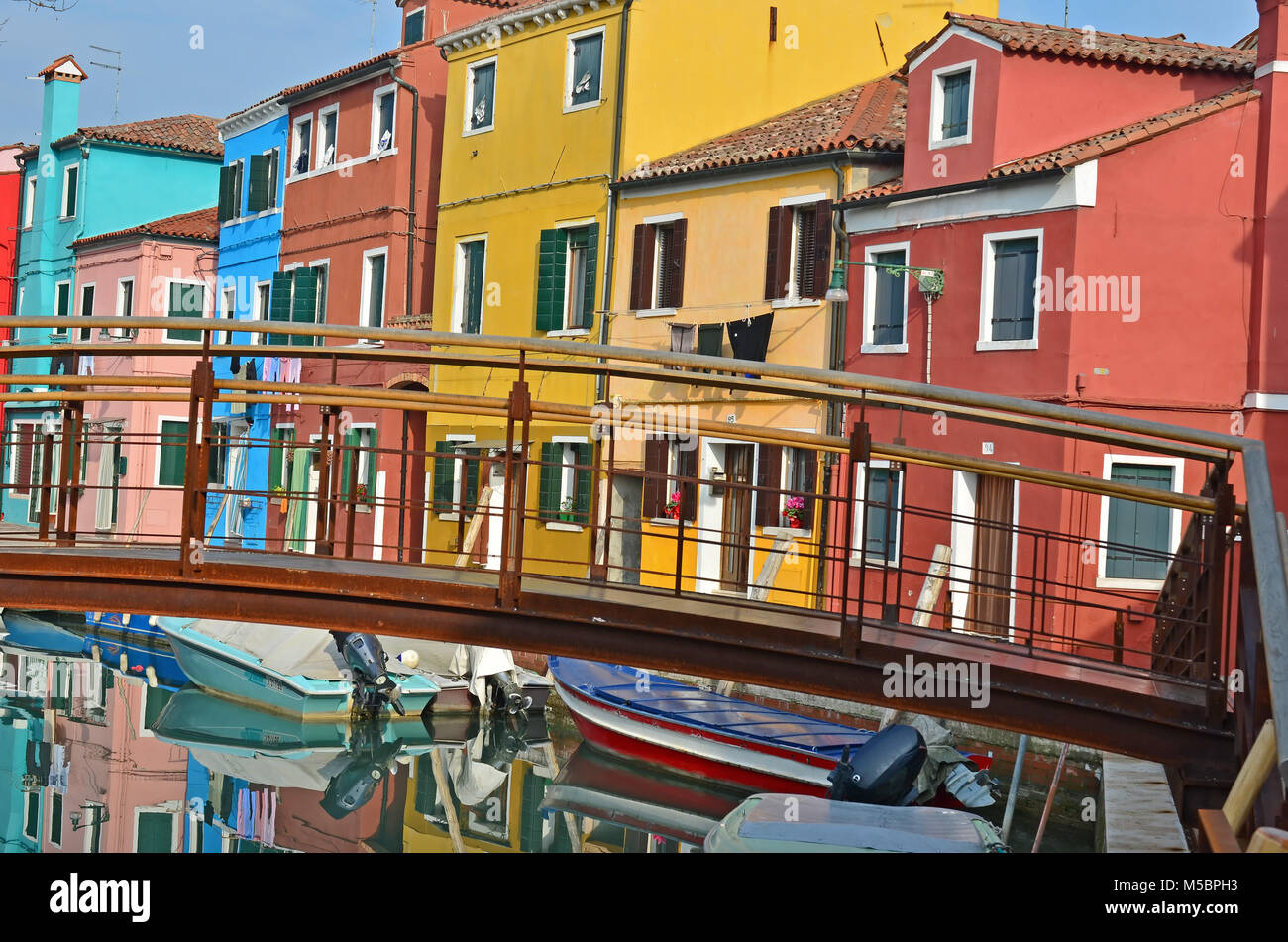 Brücke über einen Kanal mit Booten, gesäumt von bunten Häusern, auf der Insel Burano, in der Lagune Venedig Stockfoto