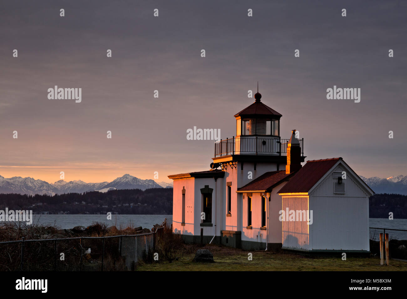 WASHINGTON - West Point Lighthouse in Seattle's Discovery Park bei Sonnenuntergang mit Blick auf die Puget Sound auf die Olympic Mountains. Stockfoto