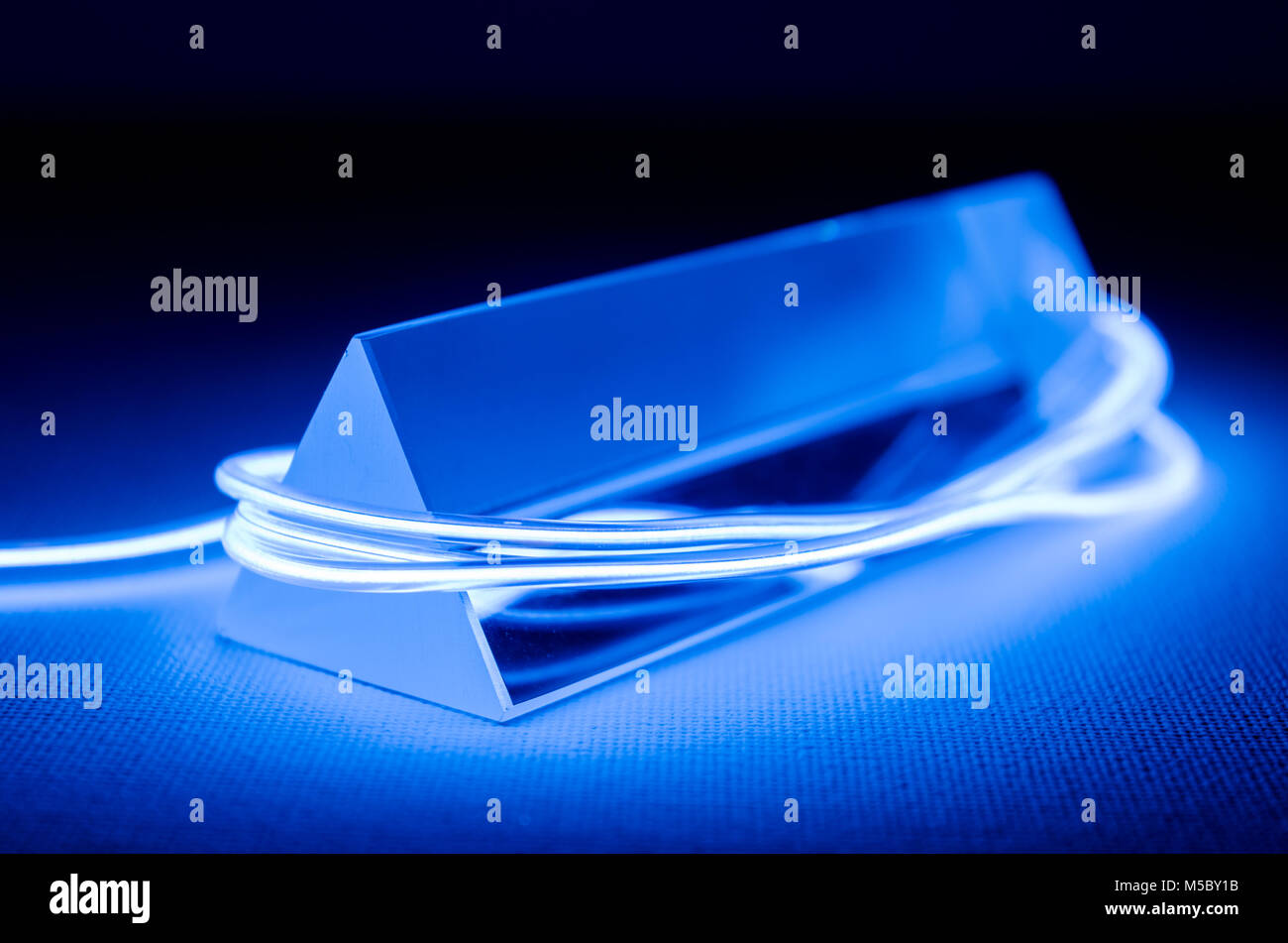 Ein Studio Still life Foto von einem dreieckigen Glasprisma mit abstrakten Neon Beleuchtung in Blau Stockfoto