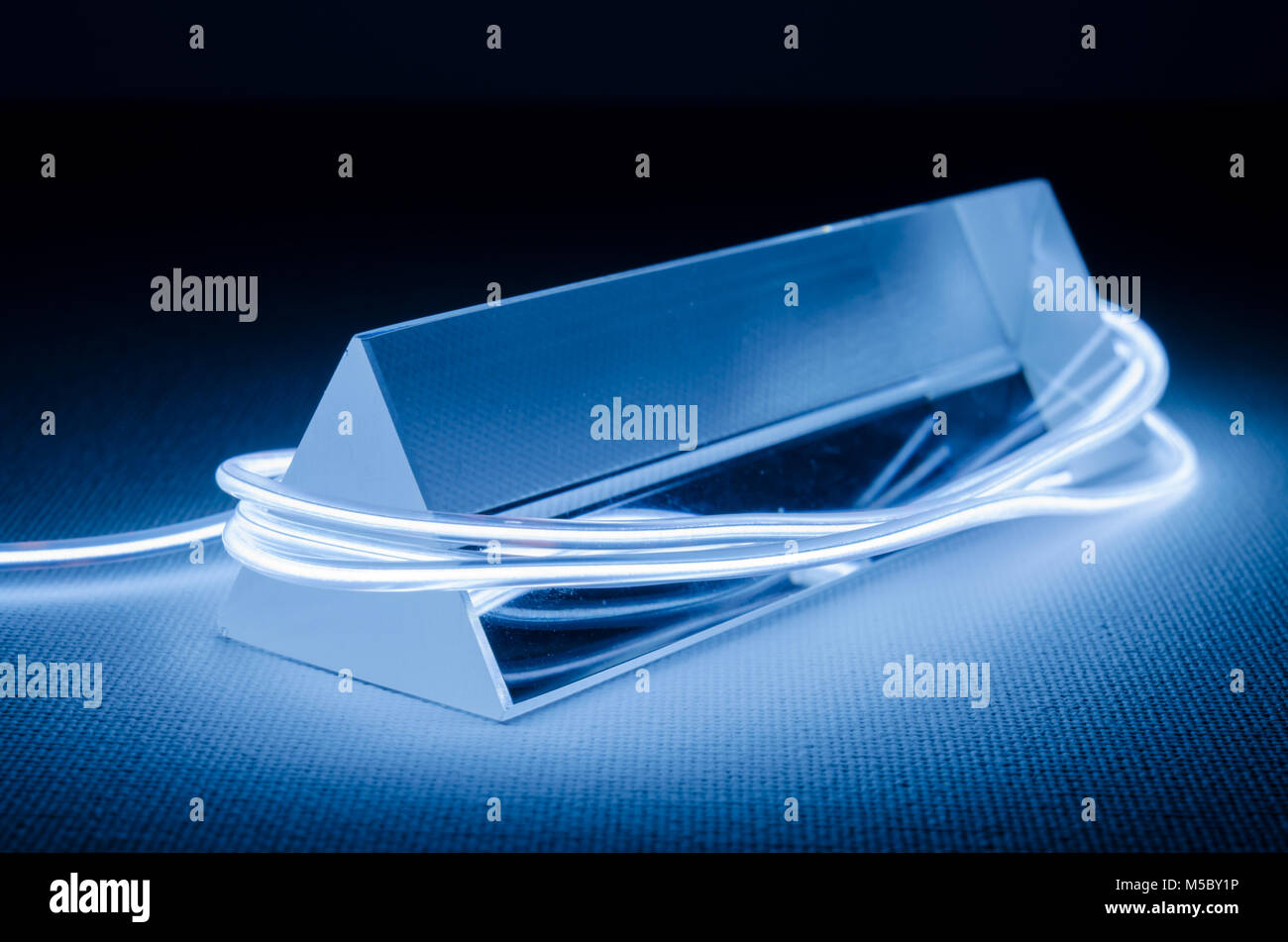 Ein Studio Still life Foto von einem dreieckigen Glasprisma mit abstrakten Neon Beleuchtung in Blau-grau Stockfoto