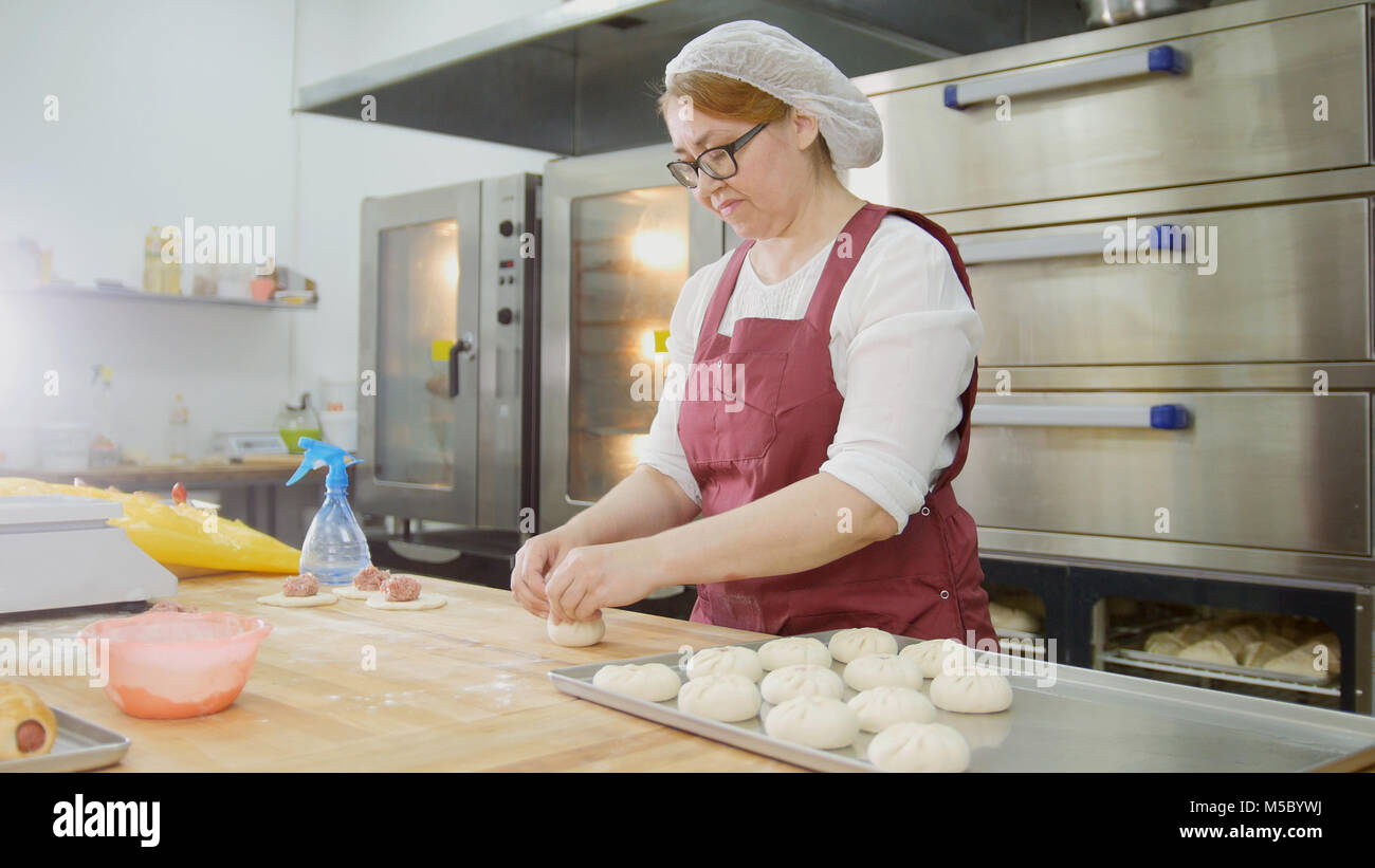 Weibliche in Gläsern und Schürze backt Kuchen in der Bäckerei Stockfoto