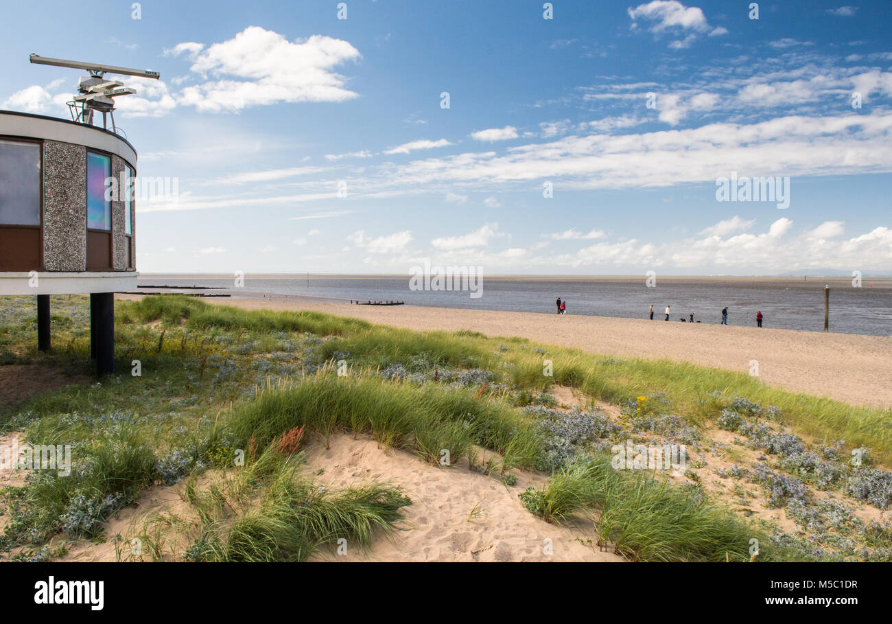 Die Menschen entlang der Sand von Fleetwood Beach in der Nähe von Blackpool, Lancashire, mit den Bergen des Lake District in die Distanz über Morecambe Stockfoto
