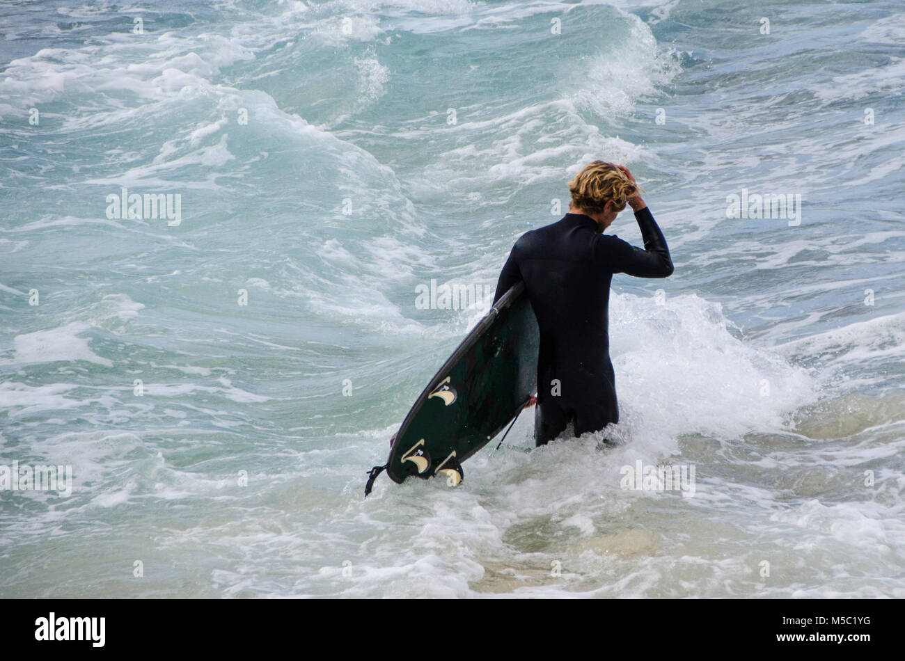 Männliche Surfer zu Fuß durch Wellen mit Surfbrett. Freiheit und Erwartung als männlich, Spaziergänge zu surfen nächste Welle. Stockfoto