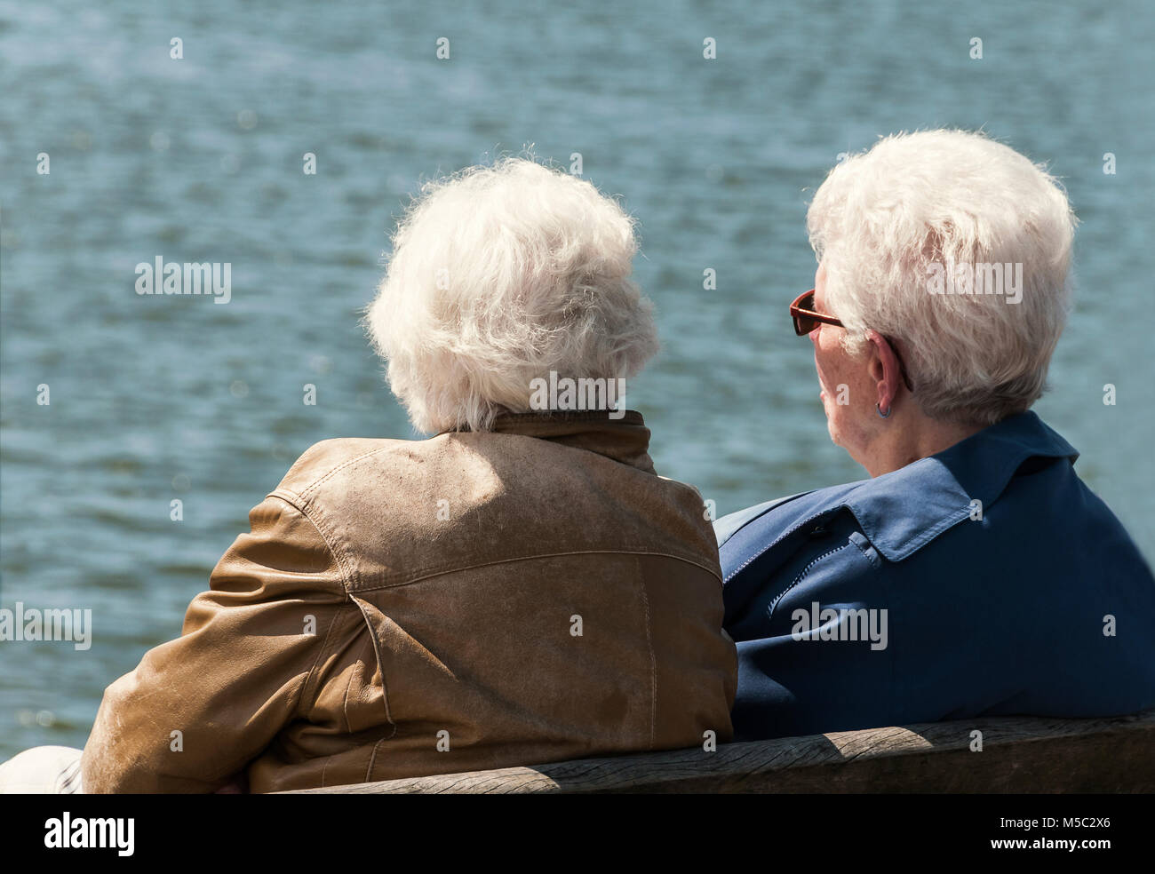 Ältere Frauen sitzen auf einer Holzbank in der Nähe der Wasser Stockfoto