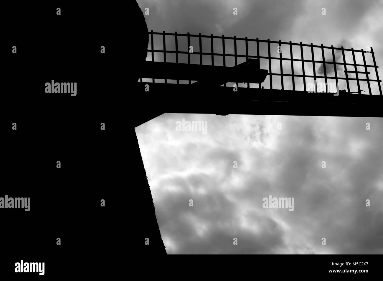 Schwarz-weiß-Ansicht einer holländischen Windmühle gegen einen grauen Himmel Stockfoto