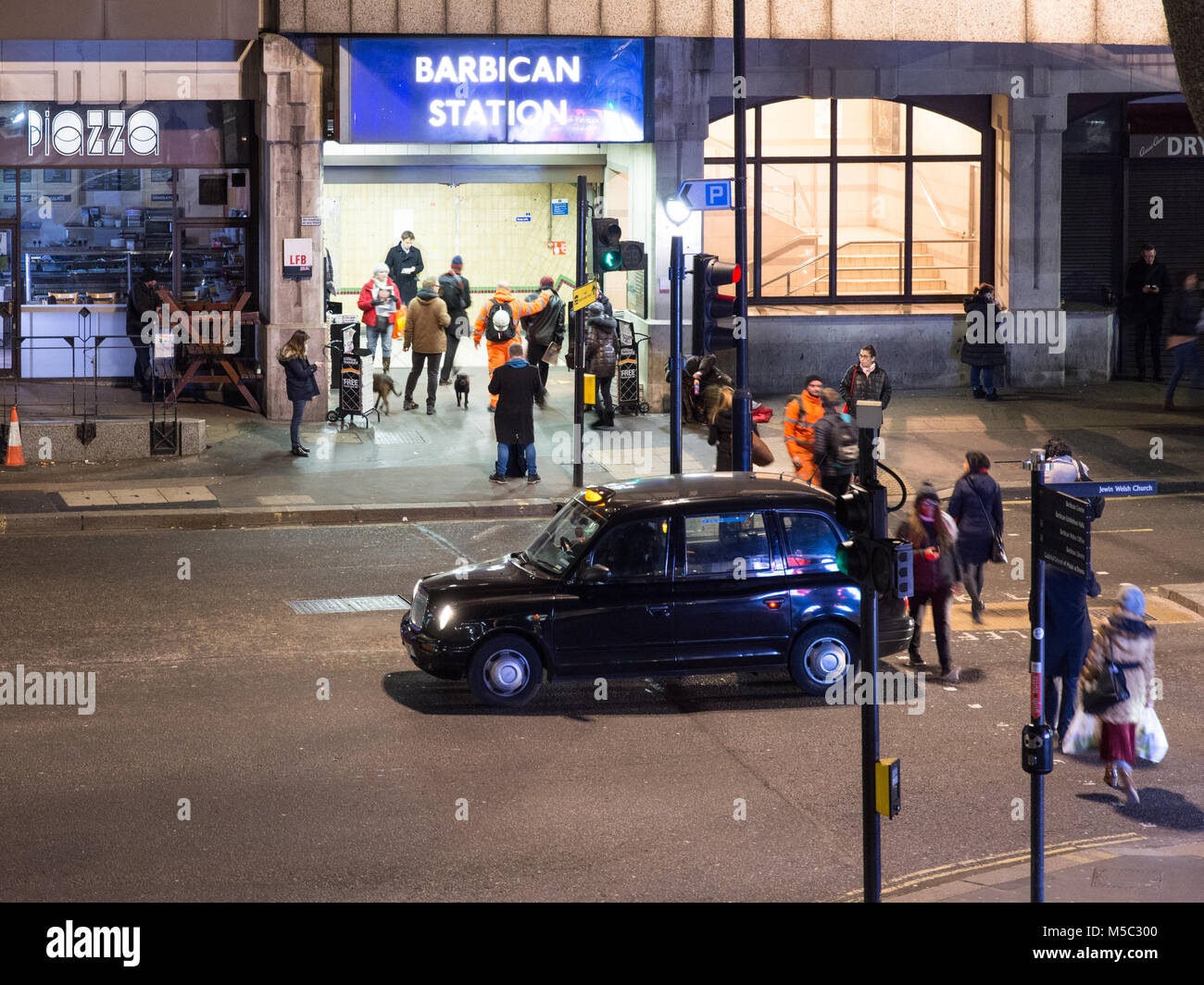 London, England, UK - Februar 8, 2018: Pendler Aldersgate Street überqueren in der Londoner City, vorbei an einer traditionellen schwarzen Londoner Taxis, Barbic zu erreichen. Stockfoto