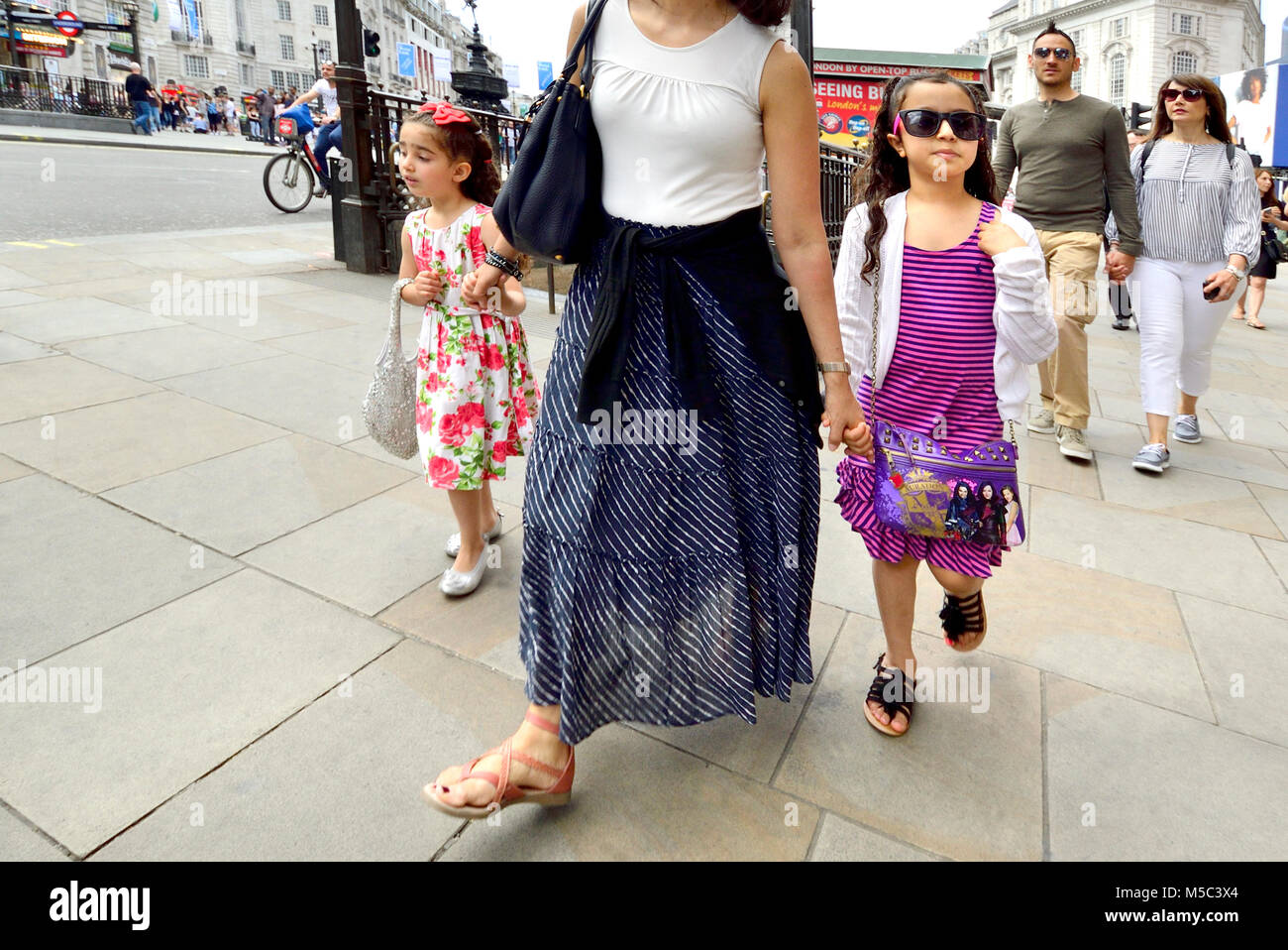 London, England, UK. Menschen in Piccadilly Circus - junge Mädchen Sonnenbrille tragen, die Hand ihrer Mutter Holding Stockfoto