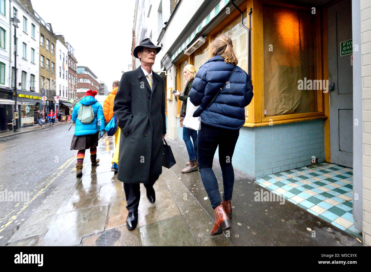 London, England, UK. Mann in einem langen Mantel und fedora Hut Stockfoto