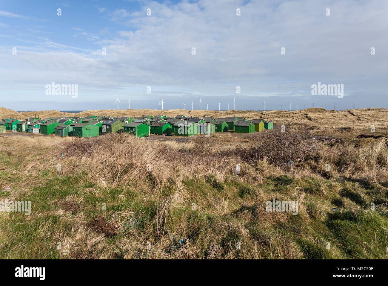 Die fishermens Hütten am South Gare, Redcar, England, Großbritannien mit Offshore- Windenergieanlagen im Hintergrund Stockfoto