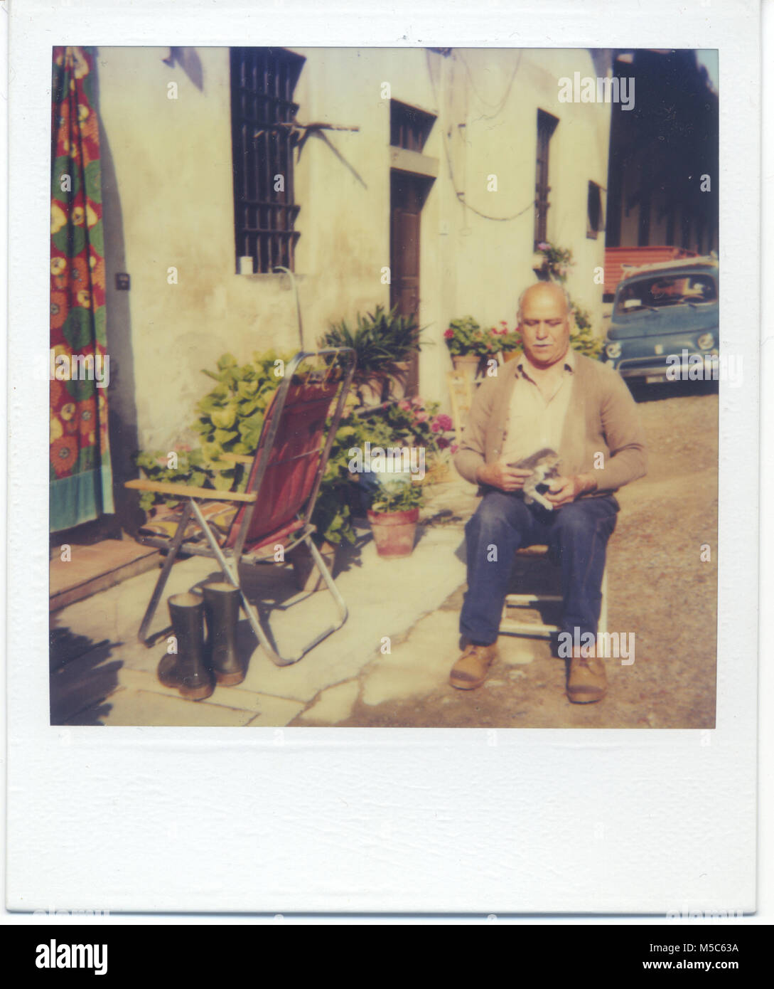 1980 s älterer Mann entspannt sich mit seiner Katze gerade vor einem Bauernhaus in der cuntryside der Toskana. Fattoria Casamora Arezzo, Italien Stockfoto