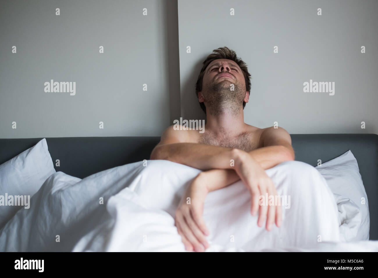 Porträt eines umgekippten junge Mann sitzt auf einem Bett allein. Stockfoto