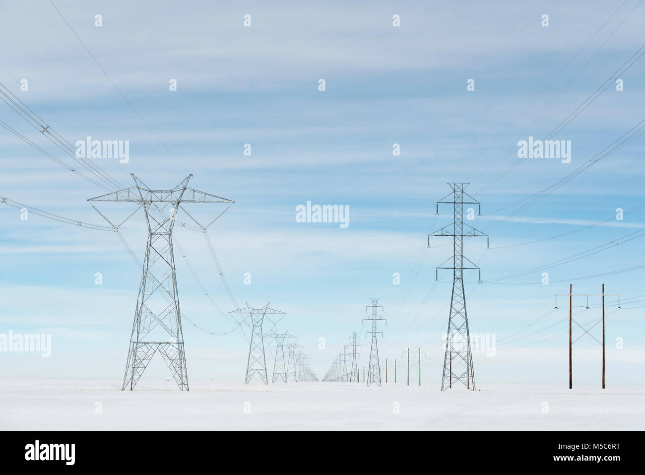 Alberta, Kanada. Blick nach unten Mitte der Zweireihige von Strommasten/Getriebe Türme auf den Prärien im Winter. Stockfoto