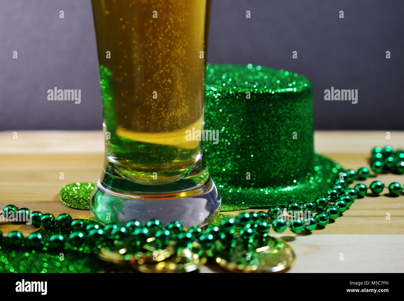 St Patricks Day Bier im Glas, irischen grünen Hut, grün Glänzende Perlen auf helle Farbe Tabelle. Kein Bier Schaum. Stockfoto