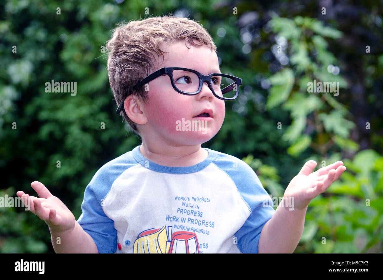 Ein neugieriger kleiner Junge in große Gläser stellt viele Fragen, die Zahl ist in der Regel eine Frage warum? Stockfoto