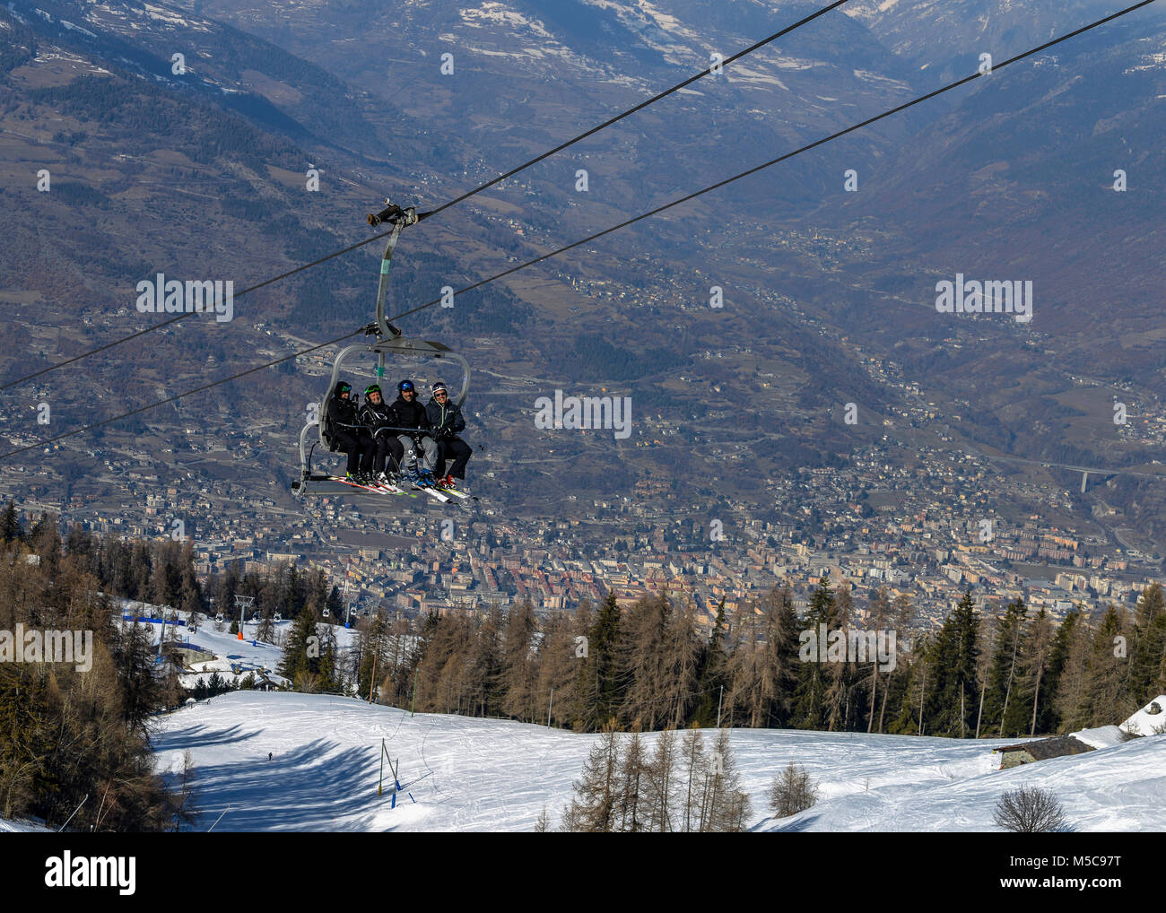 Vier Männer im mittleren Alter Skifahrer nehmen ein Sessellift auf den Berg bei Pila Skigebiet im Aostatal, Italien. Stadt Aosta, Italien Stockfoto