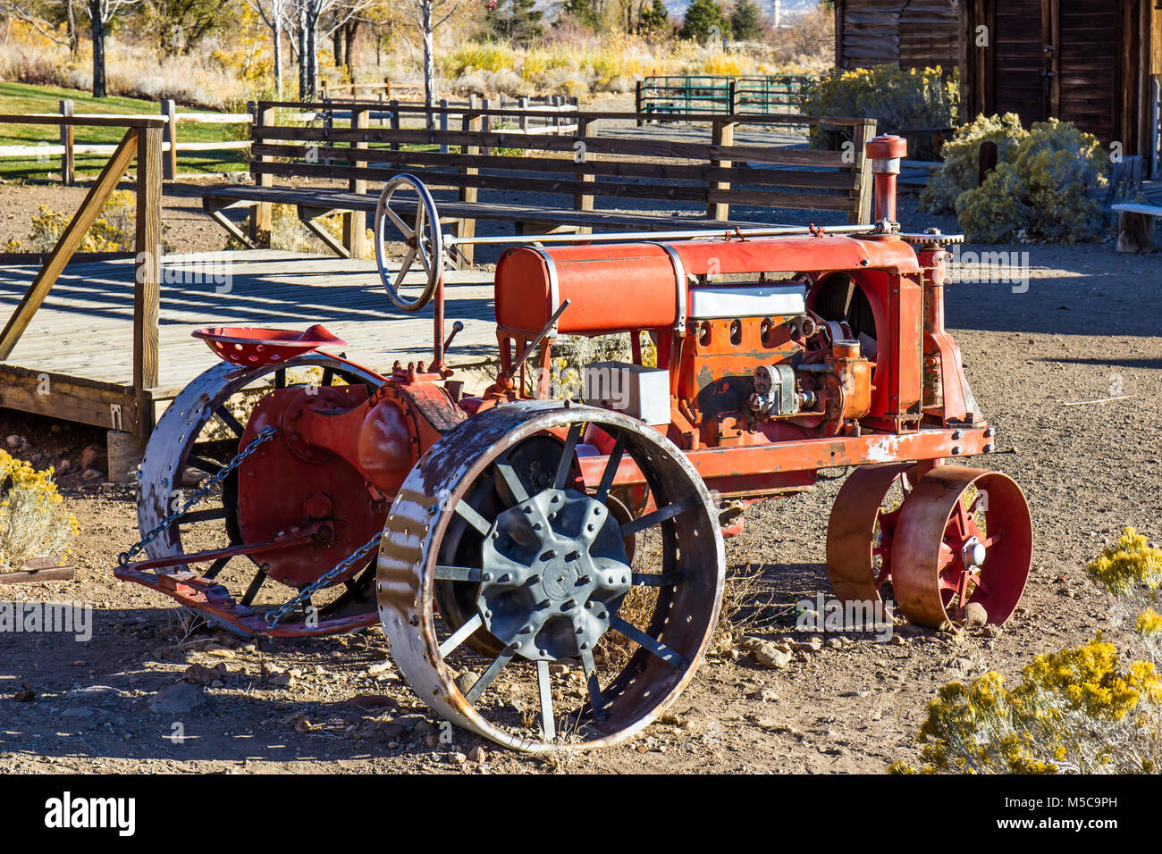 Vintage Orange Traktor mit einzigartigen eisernen Reifen im Morgenlicht Stockfoto