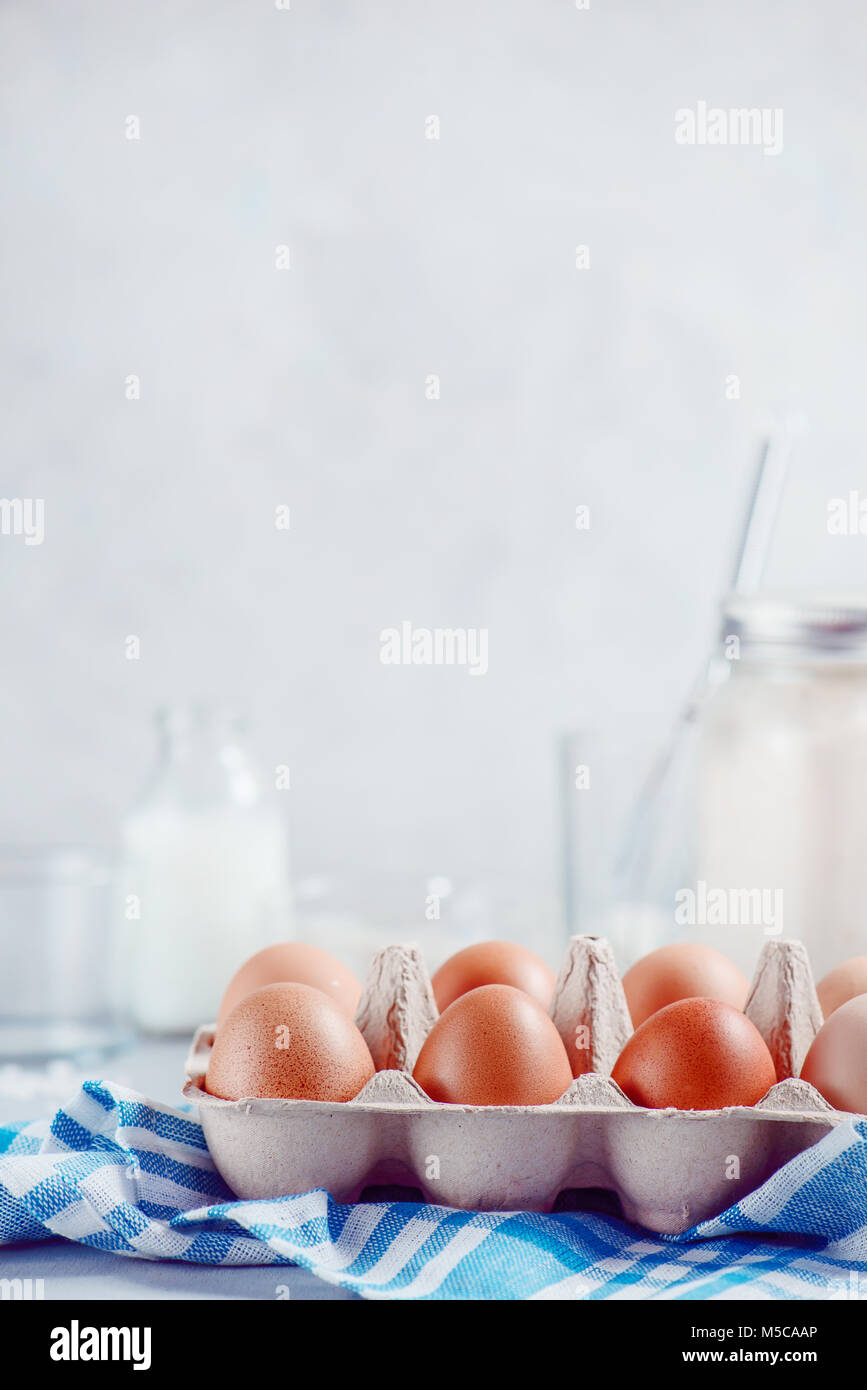 Eier in ein Papierfach auf hellem Hintergrund mit Milch, Mehl und Zutaten für Ostern kochen. High-key-Hintergrund mit kopieren. Stockfoto