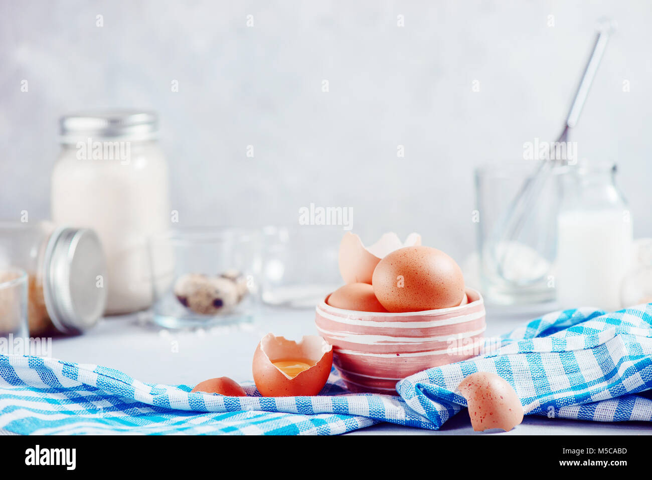 Braune Eier in eine keramische Schüssel auf einen hellen Hintergrund mit Milch, Mehl und Zutaten für Ostern kochen. High-key-Hintergrund mit kopieren. Stockfoto
