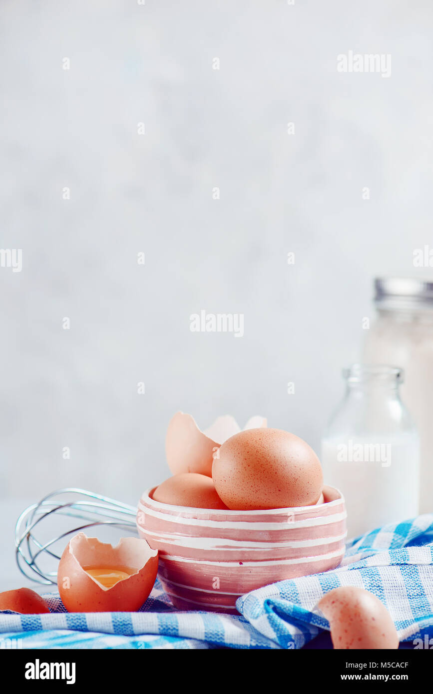 Braune Eier in eine keramische Schüssel auf einen hellen Hintergrund mit Milch, Mehl und Zutaten für Ostern kochen. High-key-Hintergrund mit kopieren. Stockfoto
