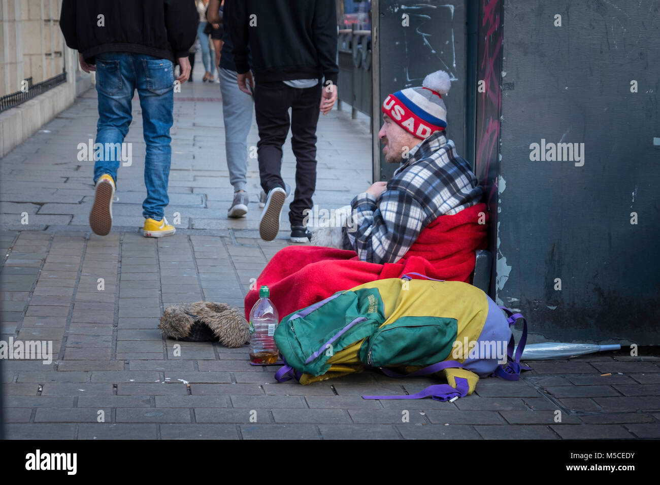 Ein obdachloser Mann sitzt mit seinem Hund in einer Stadt Straße. Stockfoto