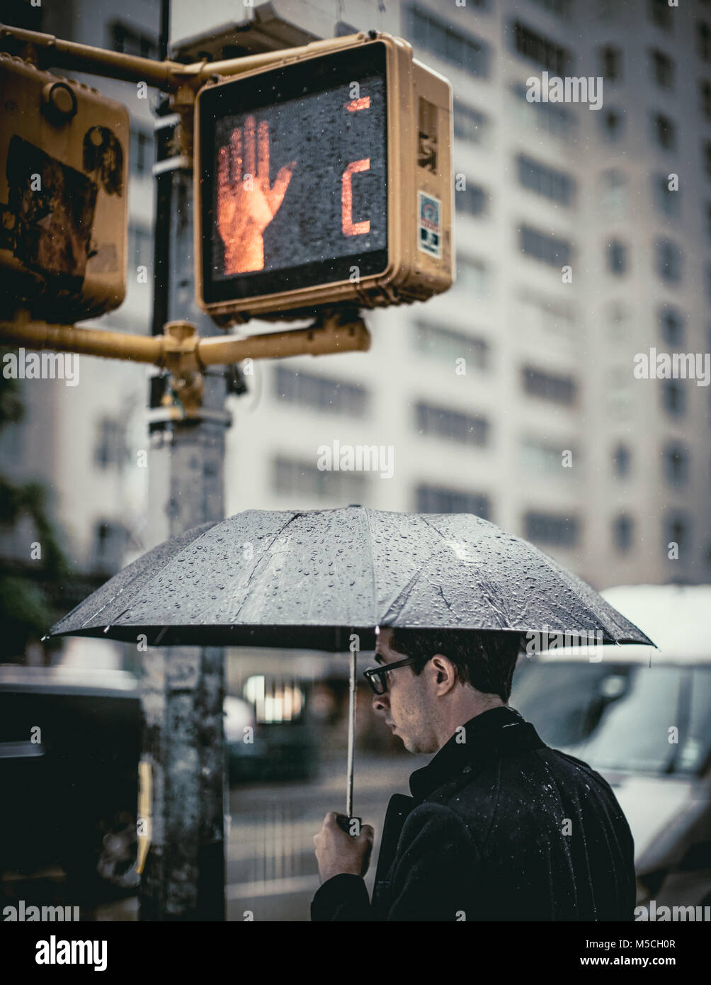 New York, Vereinigte Staaten von Amerika - 22. Mai 2017: Der Mann, der mit einem Regenschirm ist die Straße überqueren. Stockfoto