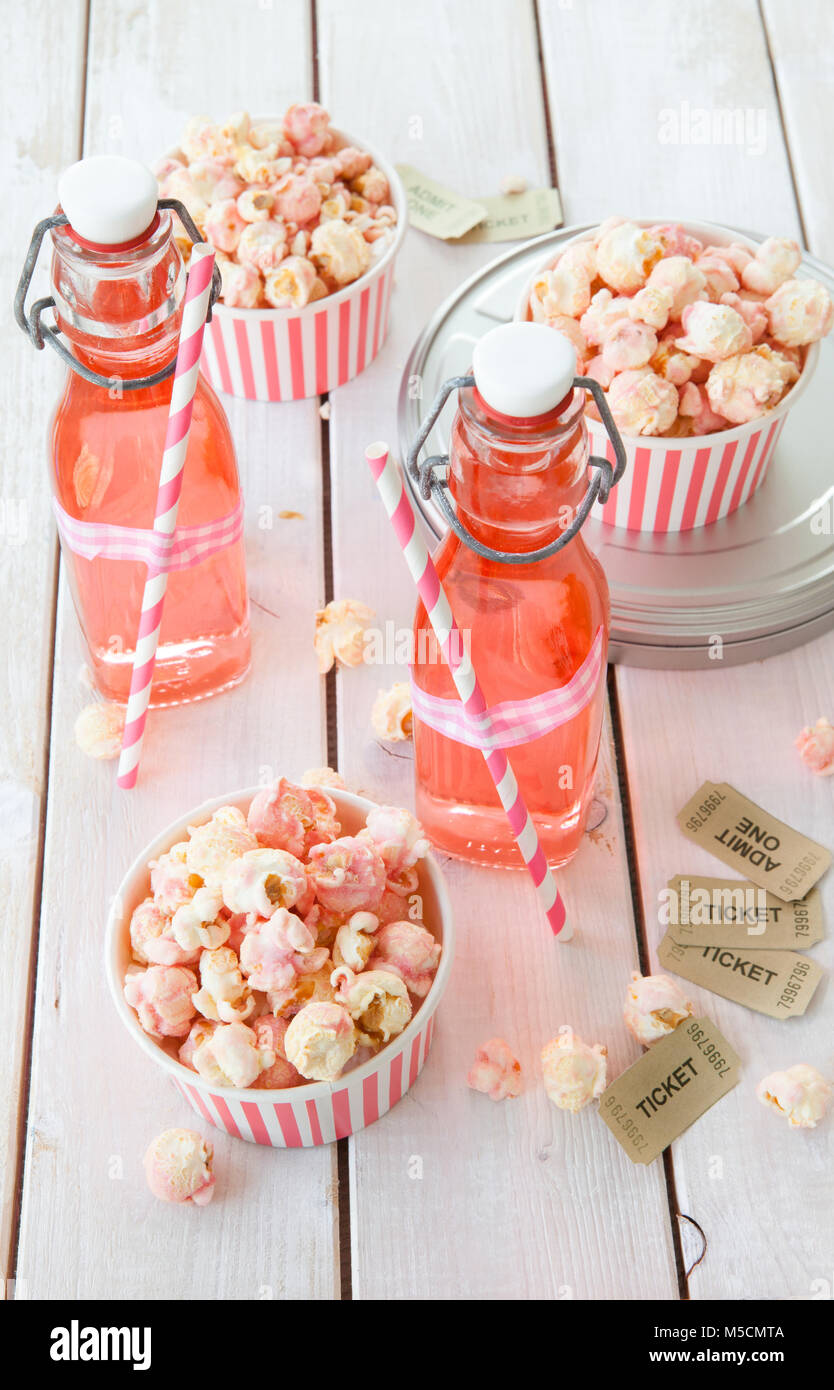 Bunte Popcorn in gestreifte Tassen und Limonade in vintage Flaschen Stockfoto