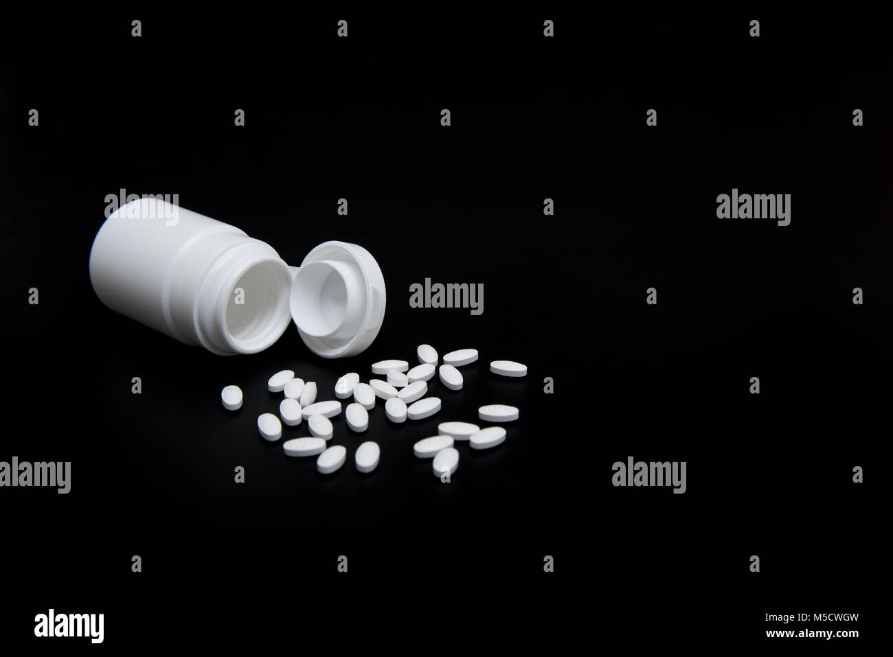 Weiße Pillen und weiße Flasche auf schwarzem Hintergrund. Mit der Kopie im Hintergrund. Für Gesundheit und medizinische Industrie Konzept verwendet. Stockfoto