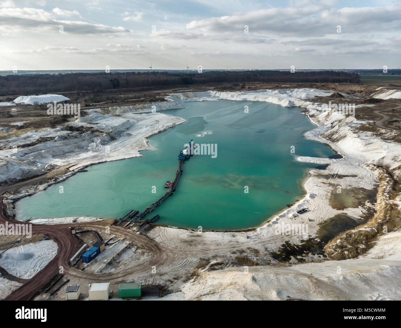 Luftbild von einem der Quarz Quarz Quarz Steinbruch Bergbau Teiche mit einem saugbagger im Vordergrund und ein dramatischer Himmel. Mit drone Gemacht Stockfoto