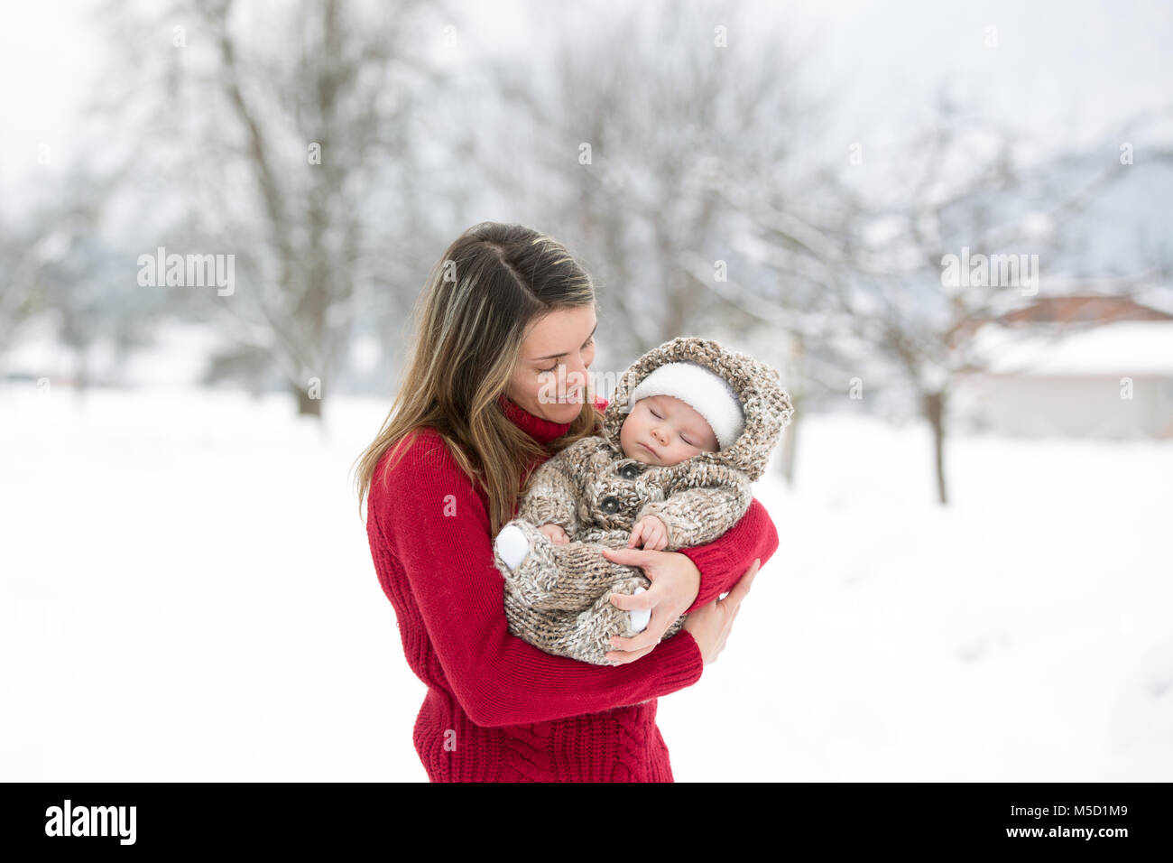 Schönen Mutter und niedlichen Baby boy in gestrickt, Body, mit ihren schönen Winter Outdoor Portrait auf einer sonnigen Winter schneebedeckten Tag genommen Stockfoto